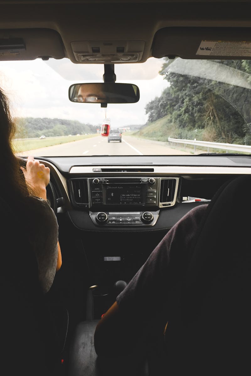 View from inside a car showing passengers looking out at an open highway, emphasizing travel and journey.